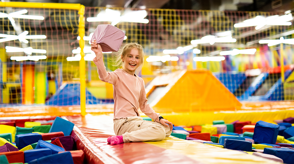 Young girl looking happy playing in a trampoline park